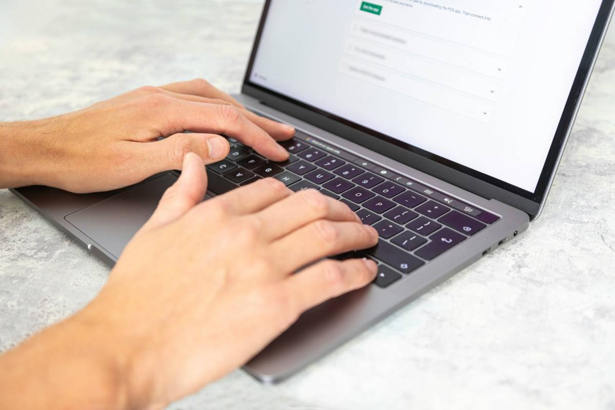 ノートパソコンのキーボードに両手を置いて操作している手元